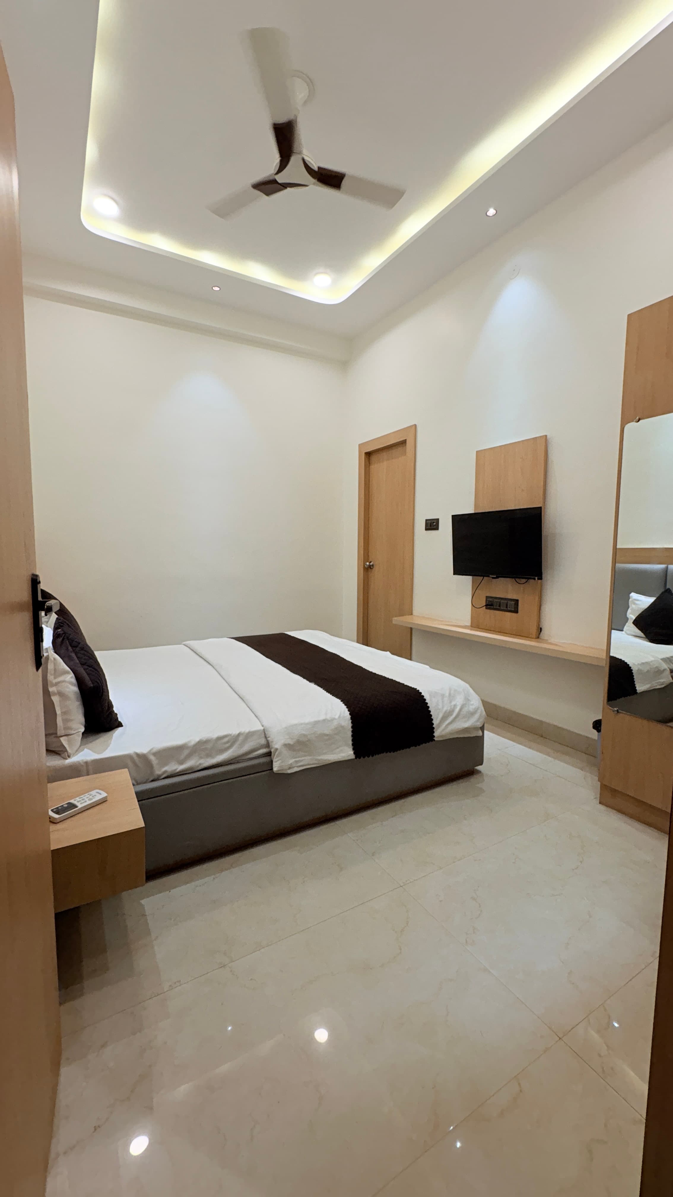 Premium double room with white linen, grey headboard, and warm cove lighting