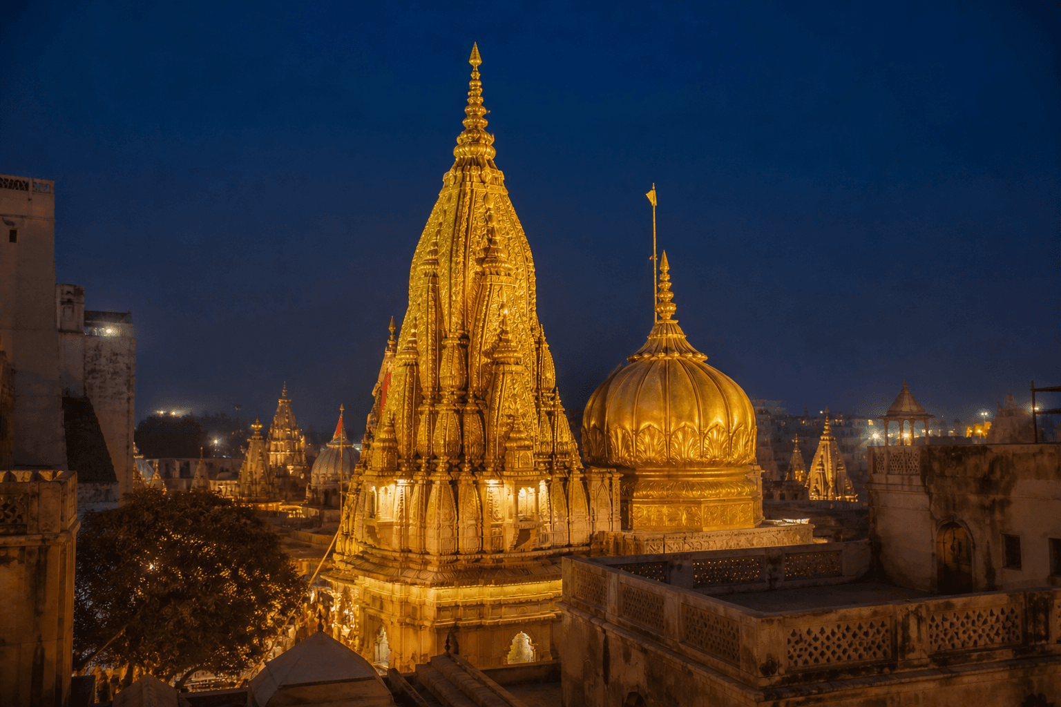 The gold spire and dome of Kashi Vishwanath temple lit against a deep blue dusk